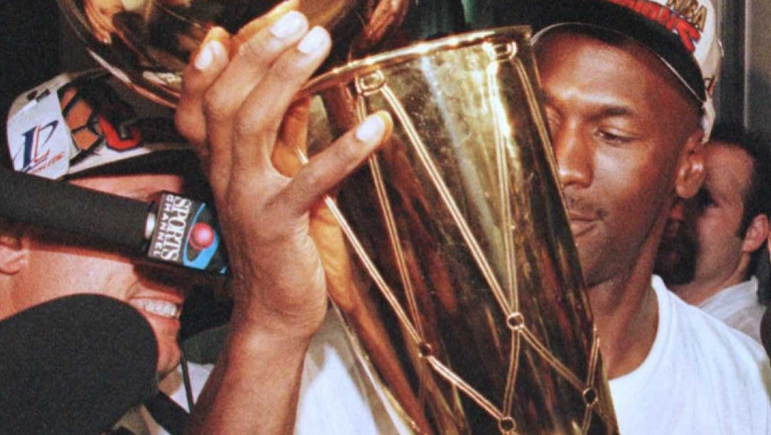 Michael Jordan of the Chicago Bulls holds the Larry O'Brian trophy outside the Bulls locker room  after game six of the NBA Finals at the United Center in Chicago, Illinois, 16 June.  The Bulls defeated the Seattle Supersonics 87-75 to win the series 4-2.     AFP PHOTO Brian BAHR (Photo by BRIAN BAHR / AFP)