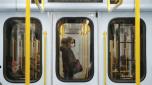 Un vagone della metropolitana di Milano con una donna con la mascherina. LaPresse