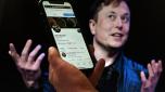 (FILES) In this file photo illustration, a phone screen displays the Twitter account of Elon Musk with a photo of him shown in the background, on April 14, 2022, in Washington, DC. - Twitter shares slid late on July 7, 2022 after a Washington Post report that Elon Musk's $44 billion deal to buy the social media giant is in danger. (Photo by Olivier DOULIERY / AFP)