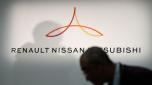 (FILES) In this file photo taken on March 12, 2019, a member of the media walks in front of a logo showing Renault, Nissan and Mitsubishi ahead of a press conference at the Nissan headquarters in Yokohama, Kanagawa prefecture. - The Nissan auto alliance said on January 27, 2022 it will invest 23 billion euros ($25.7 billion USD) into electric vehicles over the next five years as the auto industry pours resources into the sector. (Photo by Behrouz MEHRI / AFP)