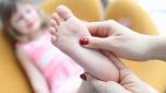 Mom giving foot massage to little girl at home closeup. Prevention of flat feet in children concept