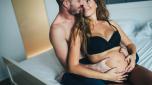 Happy pregnant woman enjoying with her handsome husband in bedroom