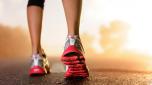 Runner feet running on road closeup on shoe. woman fitness sunrise jog workout wellness concept.