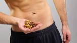 Closeup of young man's hands and abdomen holding various healthy nuts. Diet and healthy eating concept.