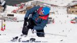 young man lying on cold snow after ski crash holding his injured knee in pain at Sierrna Nevada resort in Spain with mountains background in winter sport accident and injury concept
