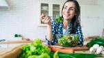 Healthy lifestyle. Good life. Organic food. Vegetables. Close up portrait of happy cute beautiful young woman while she try tasty vegan salad in the kitchen at home.