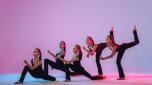 group of five teenagers balrins in black tight-fitting costumes are dancing modern konteporari on a lilac background