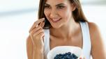 Woman On Healthy Diet. Closeup Portrait Of Beautiful Smiling Young Female With Bowl Of Tasty Ripe Sweet Blueberries ( Blue Berries ). Happy Girl Eating Organic Food. Nutrition Concept. High Resolution
