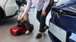 epa11336407 A child sits on a toy Tesla model in a Tesla showroom in Beijing, China, 13 May 2024. China's vehicle sales grew by 9.3 percent from the prior year to 2.36 million in April 2024, after a 9.9 percent increase in the previous month, the China Association of Automobile Manufacturers said. New energy vehicle sales accounted for 43.5 percent of total car sales in April.  EPA/WU HAO