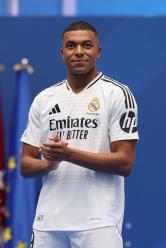 TOPSHOT - French forward Kylian Mbappe looks on during a first appearance as a Real Madrid player before fans at the Santiago Bernabeu Stadium in Madrid on July 16, 2024, after signing his new five-season contract. Still celebrating Spain's Euro 2024 triumph, Real Madrid fans have even more to cheer this July 16, 2024, as French superstar Kylian Mbappe is officially presented to a packed-out Santiago Bernabeu stadium. (Photo by Pierre-Philippe MARCOU / AFP)