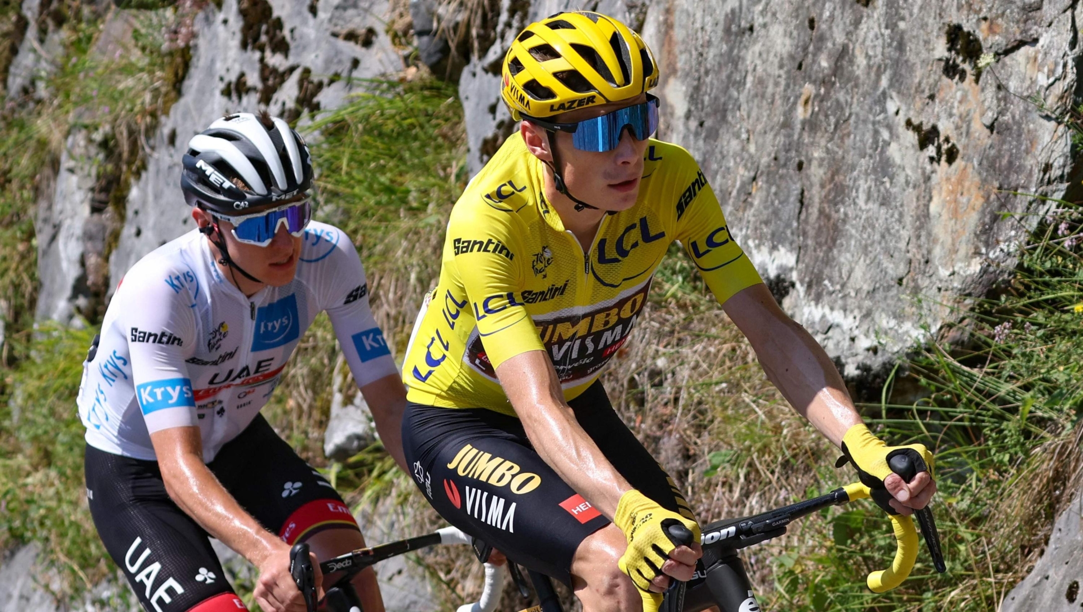 Jumbo-Visma team's Danish rider Jonas Vingegaard wearing the overall leader's yellow jersey (R) and UAE Team Emirates team's Slovenian rider Tadej Pogacar wearing the best young rider's white jersey (L) cycle with the pack of riders during the 18th stage of the 109th edition of the Tour de France cycling race, 143,2 km between Lourdes and Hautacam in the Pyrenees mountains in southwestern France, on July 21, 2022. (Photo by Thomas SAMSON / AFP)