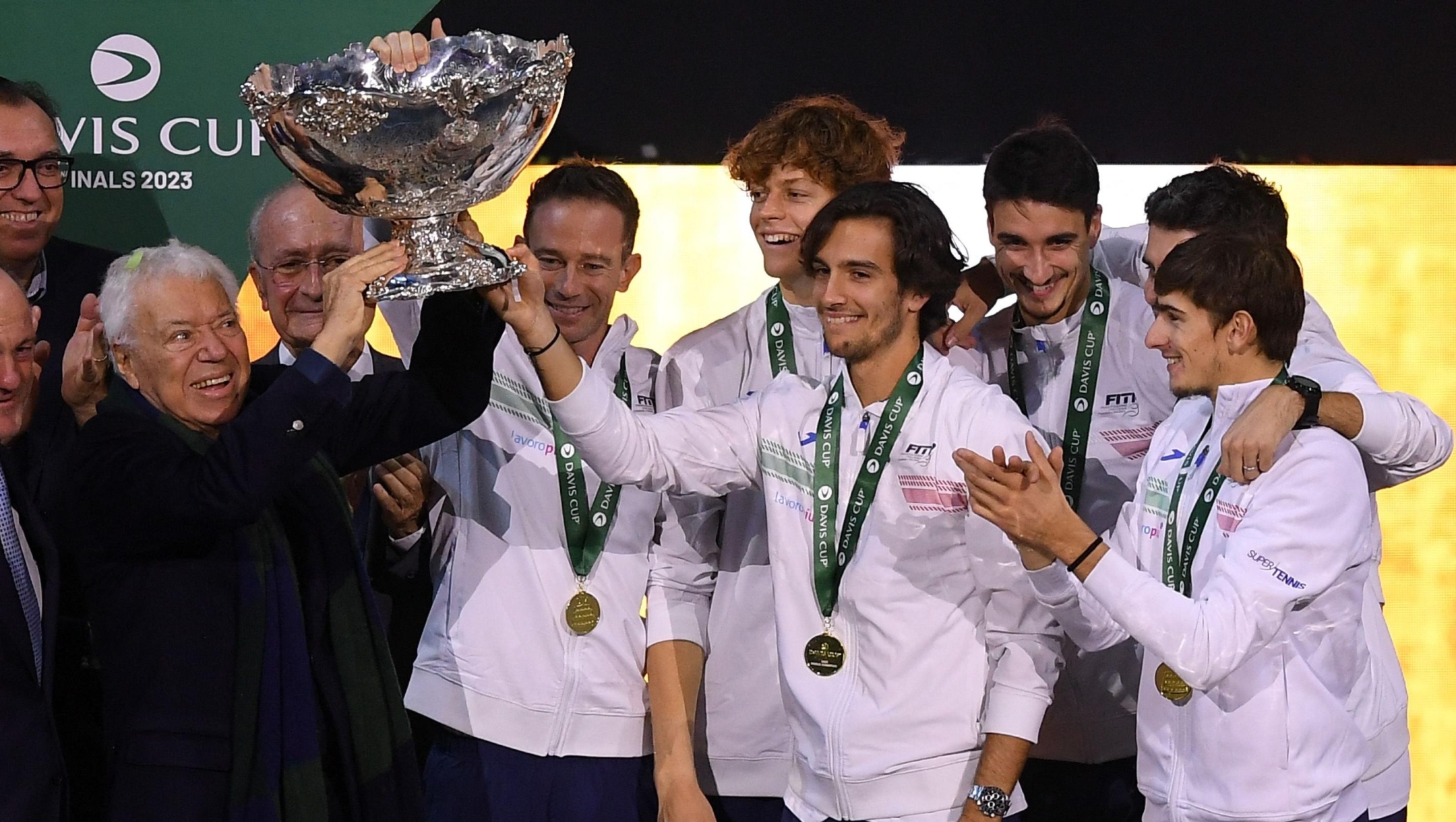 Italian tennis legend Nicola Pietrangeli (L) raises the trophy as he celebrates with the members of team Italy winning the Davis Cup tennis tournament at the Martin Carpena sportshall, in Malaga on November 26, 2023. (Photo by JORGE GUERRERO / AFP)