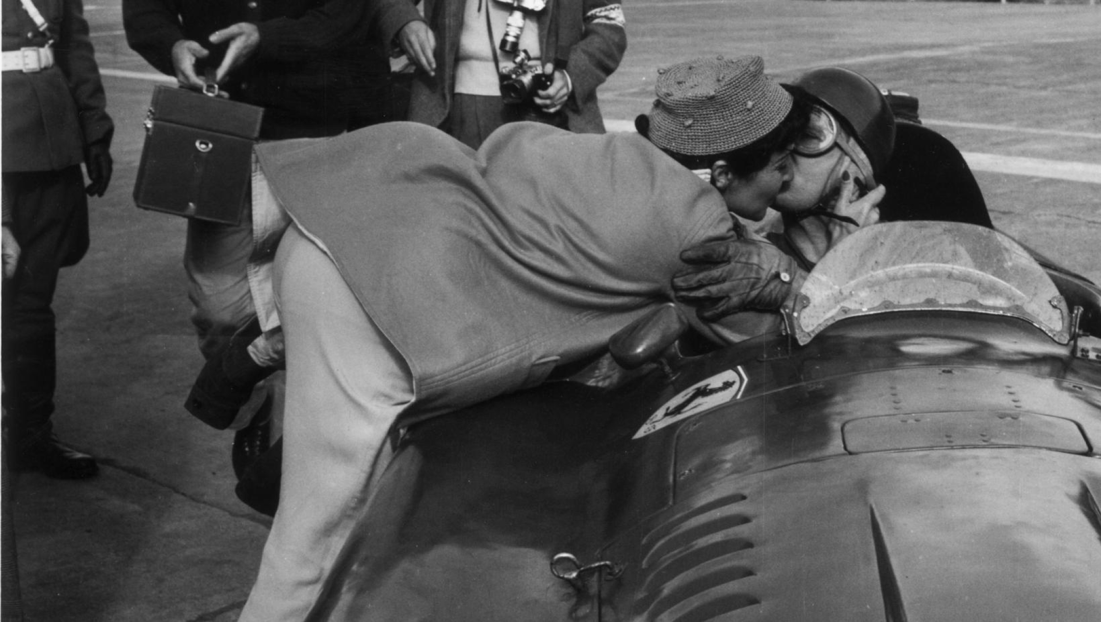 1956:  Juan Fangio of Argentina receives a kiss from his partner Andrea after winning the Geman Grand Prix in a Ferrari at the Nurburgring track.  (Photo by Keystone/Getty Images)