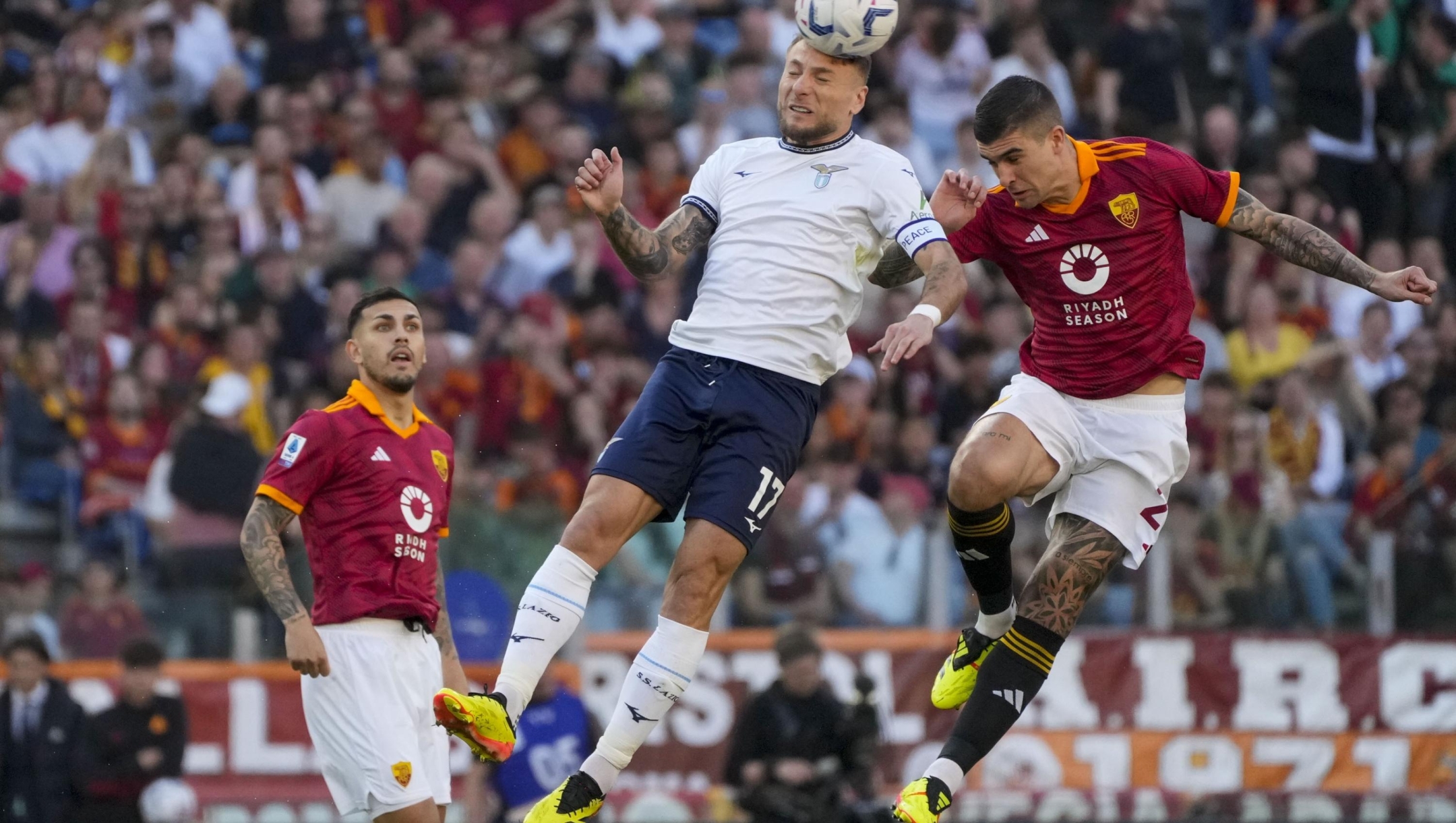 Lazio's Ciro Immobile, center, jumps for the ball with Roma's Gianluca Mancini during a Serie A soccer match between Roma and Lazio, at Stadio Olimpico, in Rome, Italy, Saturday, April 6, 2024. (AP Photo/Gregorio Borgia)