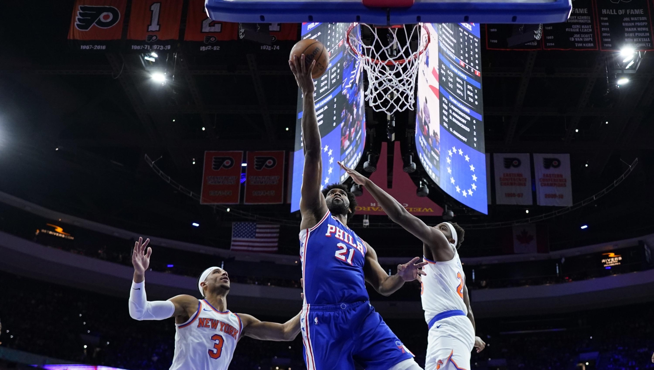 Philadelphia 76ers' Joel Embiid, center, goes up for a shot between New York Knicks' Mitchell Robinson, right, and Josh Hart during the first half of Game 3 in an NBA basketball first-round playoff series, Thursday, April 25, 2024, in Philadelphia. (AP Photo/Matt Slocum)