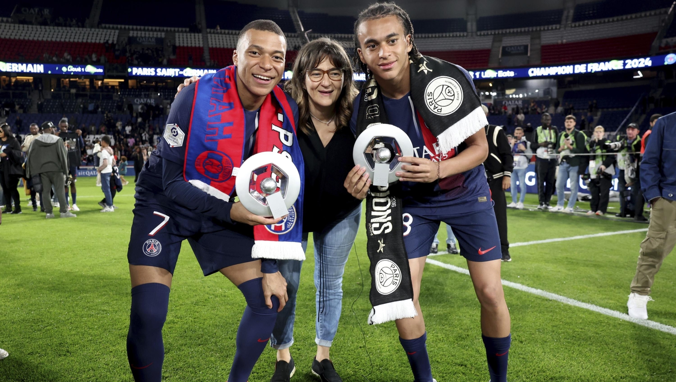 Paris Saint-Germain's French Kylian Mbappe left, and Paris Saint-Germain's Ethan Mbappe right pose with their mother Fayza Lamari as they celebrates PSG's French League One title after the French League One soccer match between Paris Saint-Germain and Toulouse at the Parc des Princes stadium in Paris, Sunday, May 12, 2024. (Franck Fife, Pool via AP)