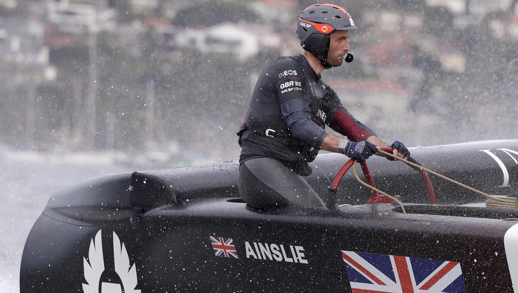 FILE - Skipper Ben Ainslie steers the boat as the British team crosses the finish line in the second fleet race of the SailGP series in Sydney, Feb. 29, 2020. (AP Photo/Rick Rycroft, File)