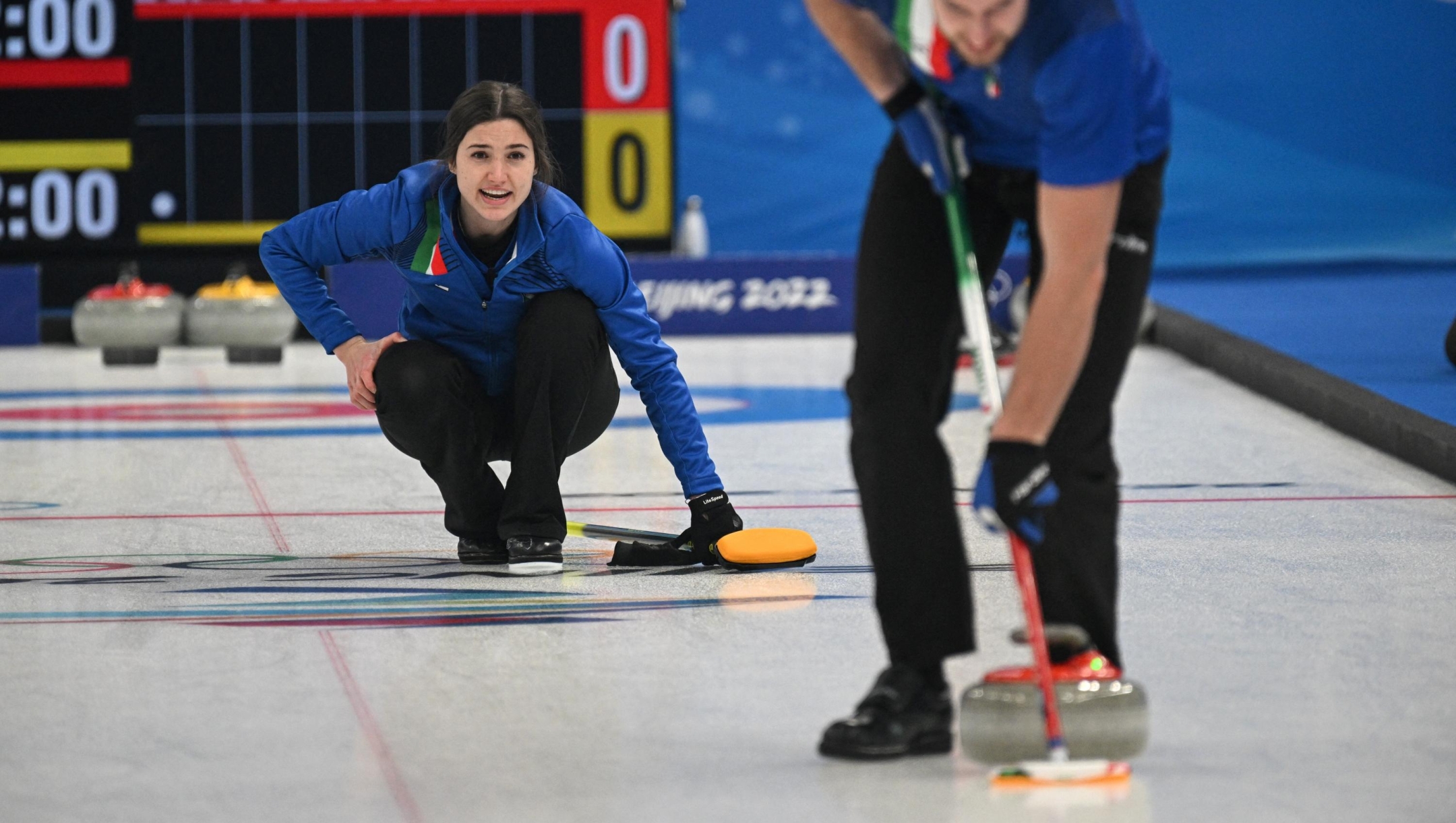 Italy’s Stefania Constantini (L) gives directions as Italy’s Amos Mosaner (R) sweeps during the mixed doubles round robin session 3 game of the Beijing 2022 Winter Olympic Games curling competition between Italy and Switzerland, at the National Aquatics Centre in Beijing on February 3, 2022. (Photo by LILLIAN SUWANRUMPHA / AFP)