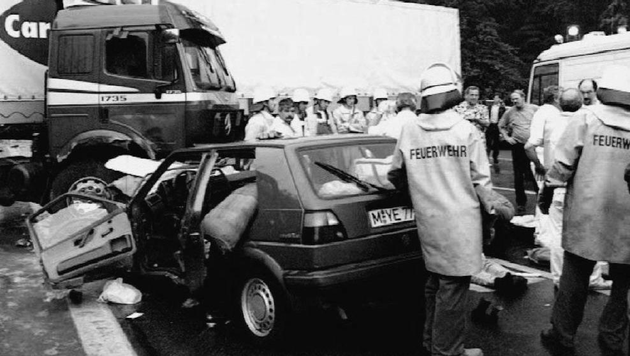Firemen stand next to the wrecked car of Croatian basketball player Drazen Petrovic, who was killed late 07 June when his car crashed into a truck on Germany's A9 motorway. Petrovic was one of the top scorers in the U.S. NBA basketball championships. (B/W) (Photo by dpa Picture-Alliance via AFP)