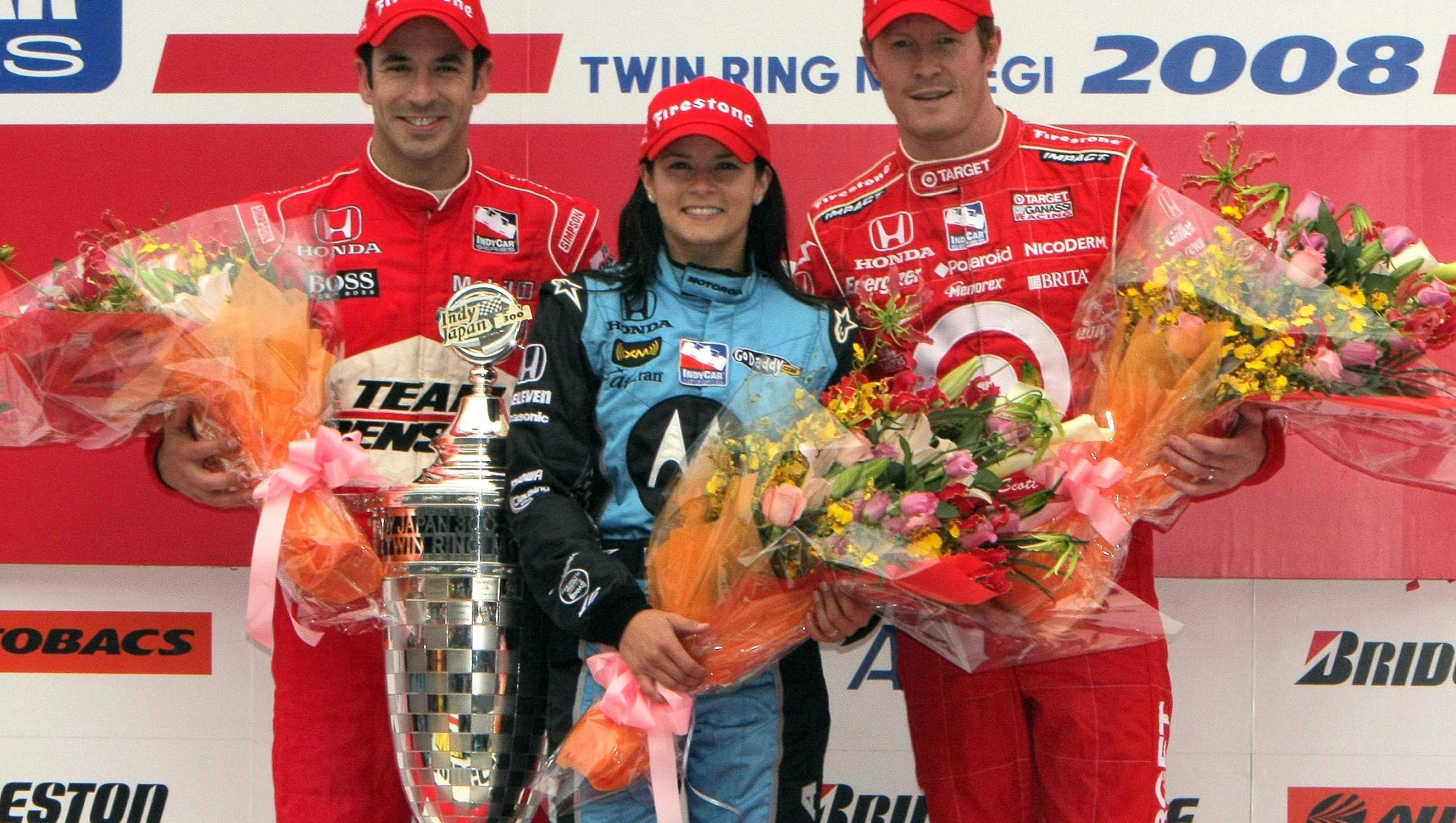 US Indy driver and winner of the Indy Japan 300, Danica Patrick (C), poses with second-placed Helio Castroneves of Brazil (L) and third-placed Scott Dixon of New Zealand (R) on the podium at the Twin Ring Motegi racecourse in Motegi on April 20, 2008. Patrick covered 200 laps over the 1.52-mile (2.5-kilometre) Twin Ring Motegi oval in one hour, 51 minutes, 02.6739 to become the first female Indy Car winner.  AFP PHOTO/JIJI PRESS (Photo by AFP / JIJI PRESS / AFP) / Japan OUT