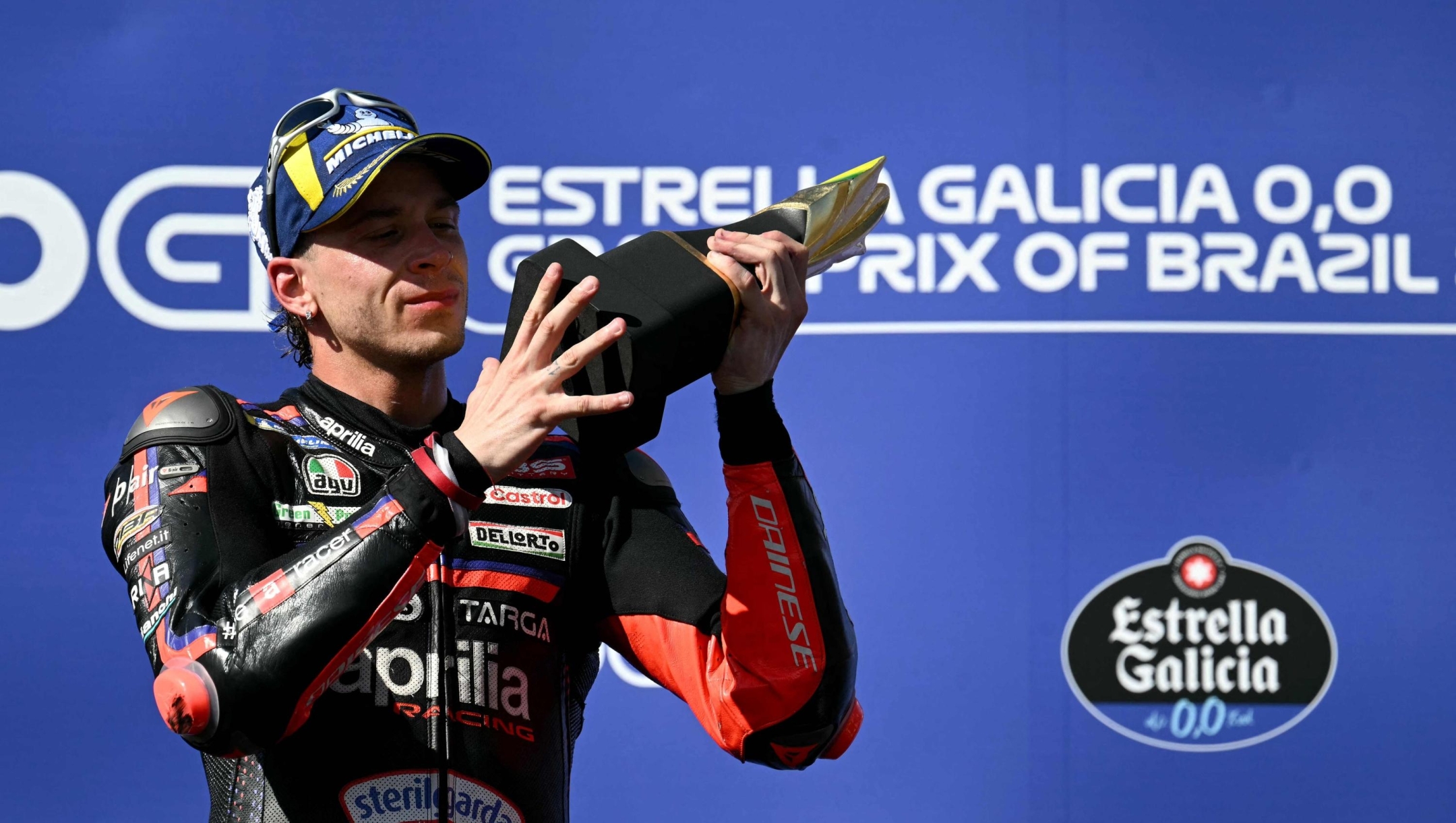 Aprilia Racing's Italian rider Marco Bezzecchi celebrates with the trophy on the podium after winning the MotoGP Grand Prix of Brazil at the Ayrton Senna International racetrack in Goiania, state of Goias, Brazil, on March 22, 2026. (Photo by EVARISTO SA / AFP)