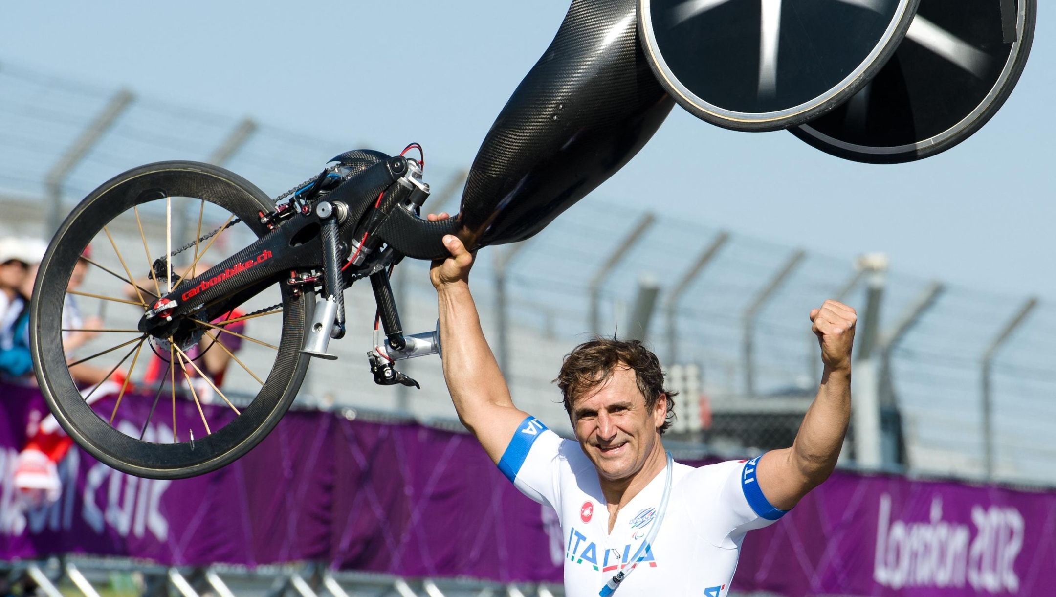 Italy's Alessandro Zanardi holds his bike aloft as he celebrates after winning the gold medal in the men's individual H4 time trial cycling final during the London 2012 Paralympic Games at Brands Hatch circuit, in Kent, southern England on September 5, 2012.  AFP PHOTO / LEON NEAL (Photo by LEON NEAL / AFP)