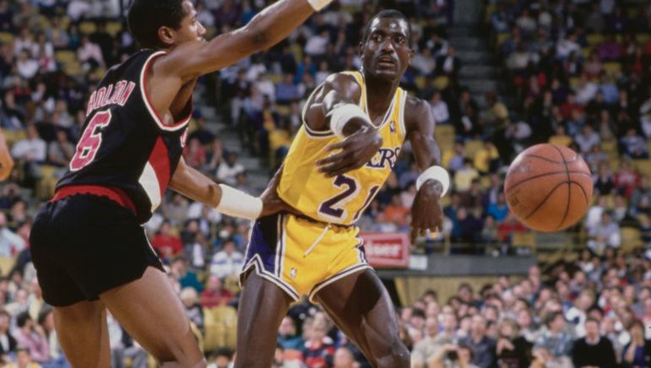 Michael Cooper #21, Shooting Guard for the Los Angeles Lakers passes the basketball by Michael Holton #6, Point Guard of the Portland Trail Blazers during their NBA Pacific Division basketball game on 12th March 1987 at The Forum arena in Inglewood, Los Angeles, California, United States. The Lakers won the game 125 - 116.  (Photo by Stephen Dunn/Allsport/Getty Images)