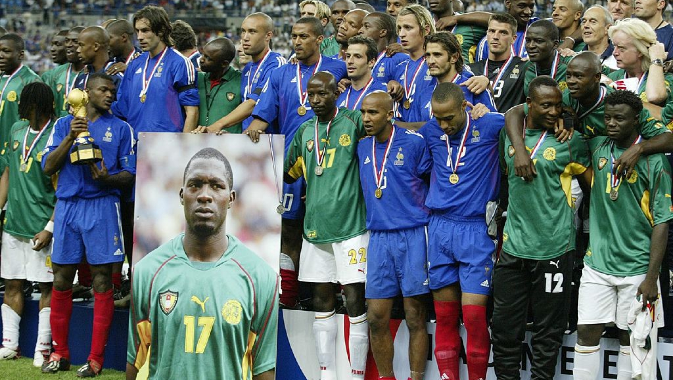 PARIS, FRANCE - JUNE 29:  Confederations Cup 2003 Finale, Paris; Kamerun - Frankreich (CMR - FRA) 0:1; Spieler Frankreichs und Kameruns halten ein Foto von Marc-Vivien FOE/CMR, der wenige Tage zuvor auf dem Fussballplatz gestorben ist.  (Photo by Henri Szwarc/Bongarts/Getty Images)