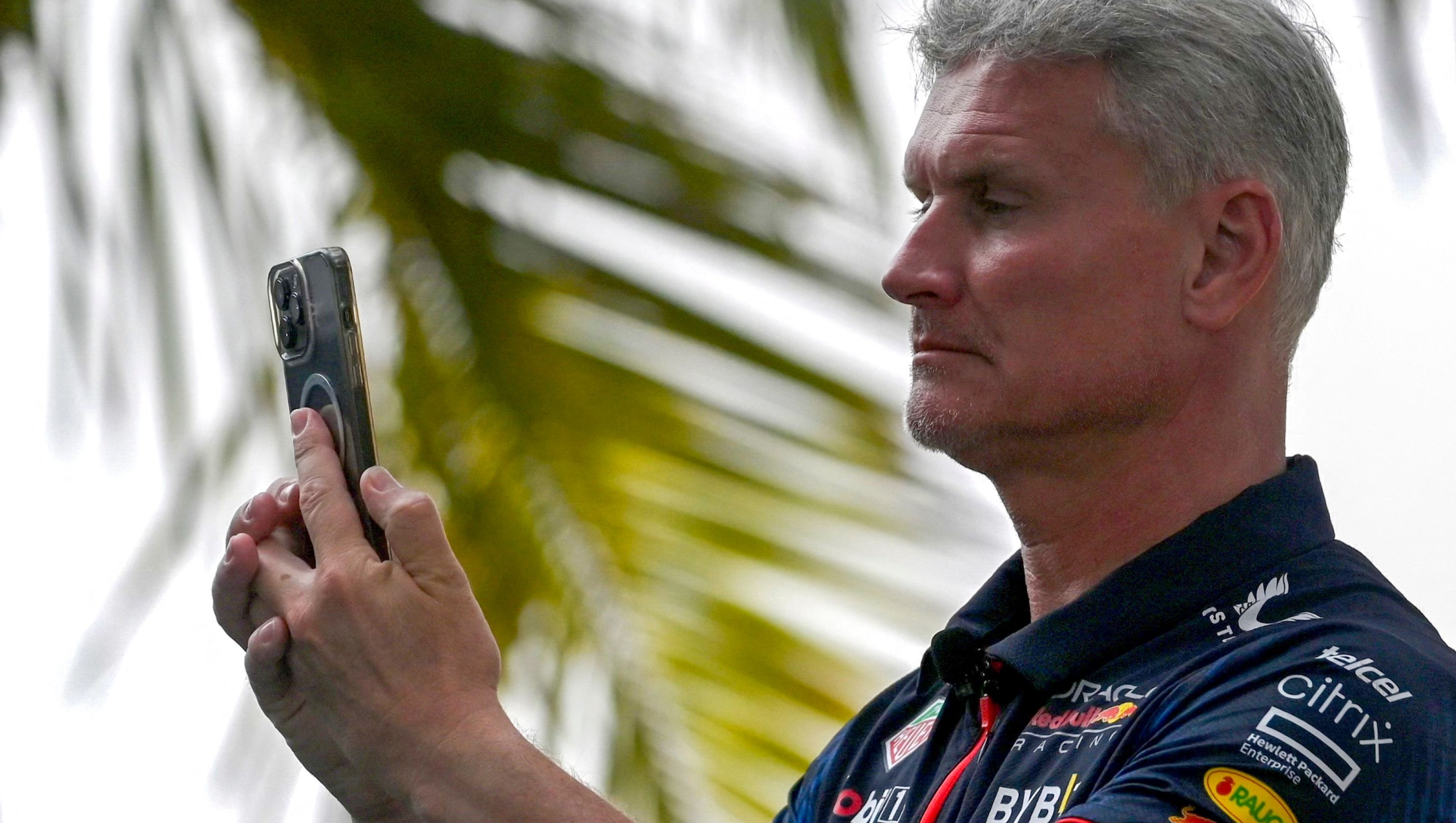 Britain's former Formula One driver David Coulthard takes pictures with his phone during a press conference in Mumbai on March 11, 2023. (Photo by Indranil MUKHERJEE / AFP)