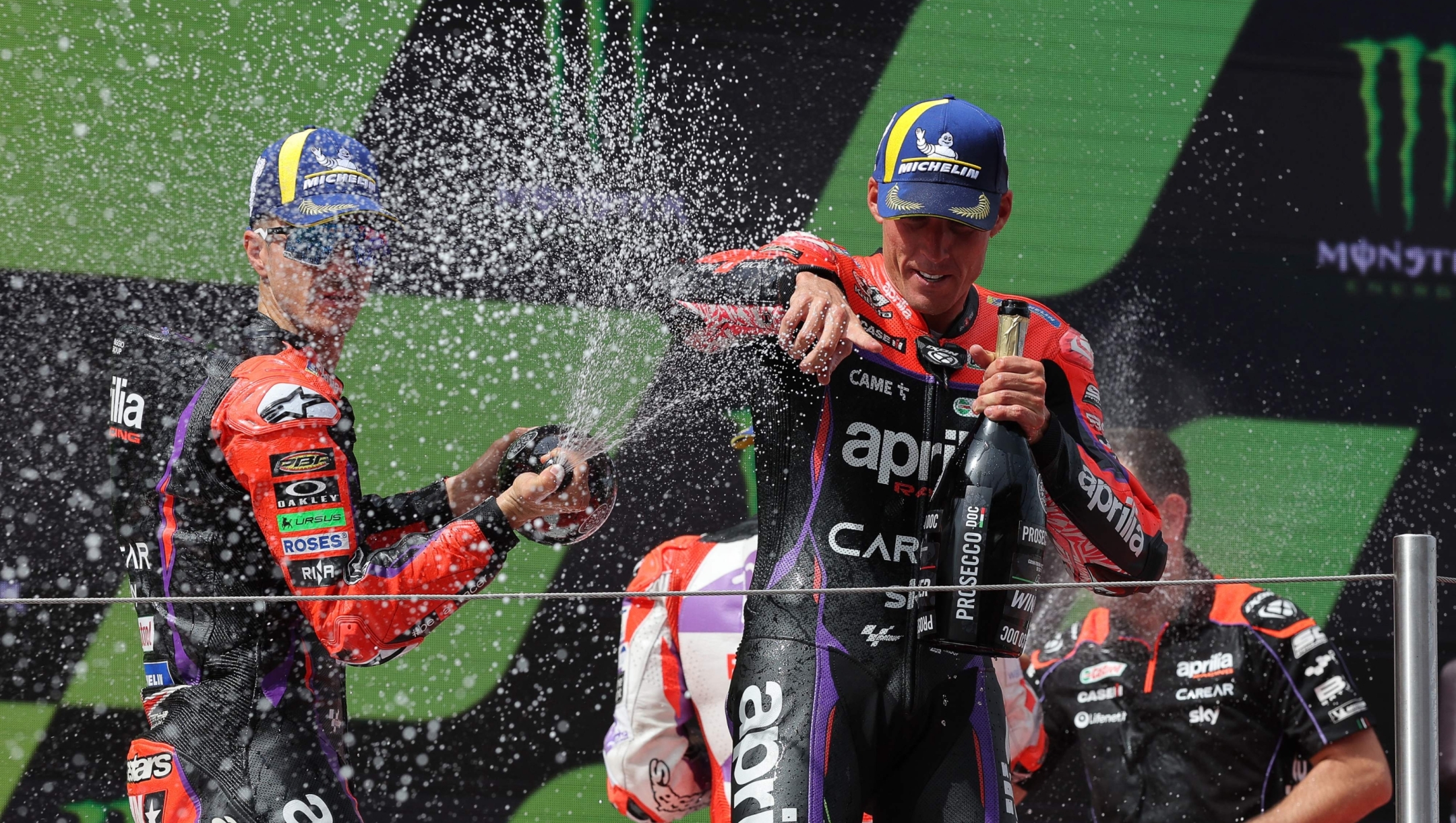 Aprilia Spanish rider Aleix Espargaro (R) celebrates on the podium with Aprilia Spanish rider Maverick Vinales after winning the MotoGP race of the Moto Grand Prix de Catalunya at the Circuit de Catalunya in Montmelo, on the outskirts of Barcelona, on September 3, 2023. (Photo by LLUIS GENE / AFP)