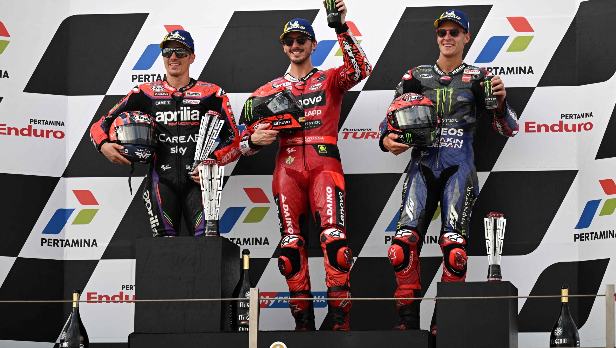 First-placed Ducati Lenovo Teams Italian rider Francesco Bagnaia (C), Second-placed Aprilia racings Spanish rider Maverick Vinales (L), and third-placed Monster Energy Yamaha MotoGP's French rider Fabio Quartararo celebrate during the podium ceremony after competing in the Indonesian Grand Prix MotoGP at the Mandalika International Circuit in Kuta Mandalika, Central Lombok on October 15, 2023. (Photo by SONNY TUMBELAKA / AFP)