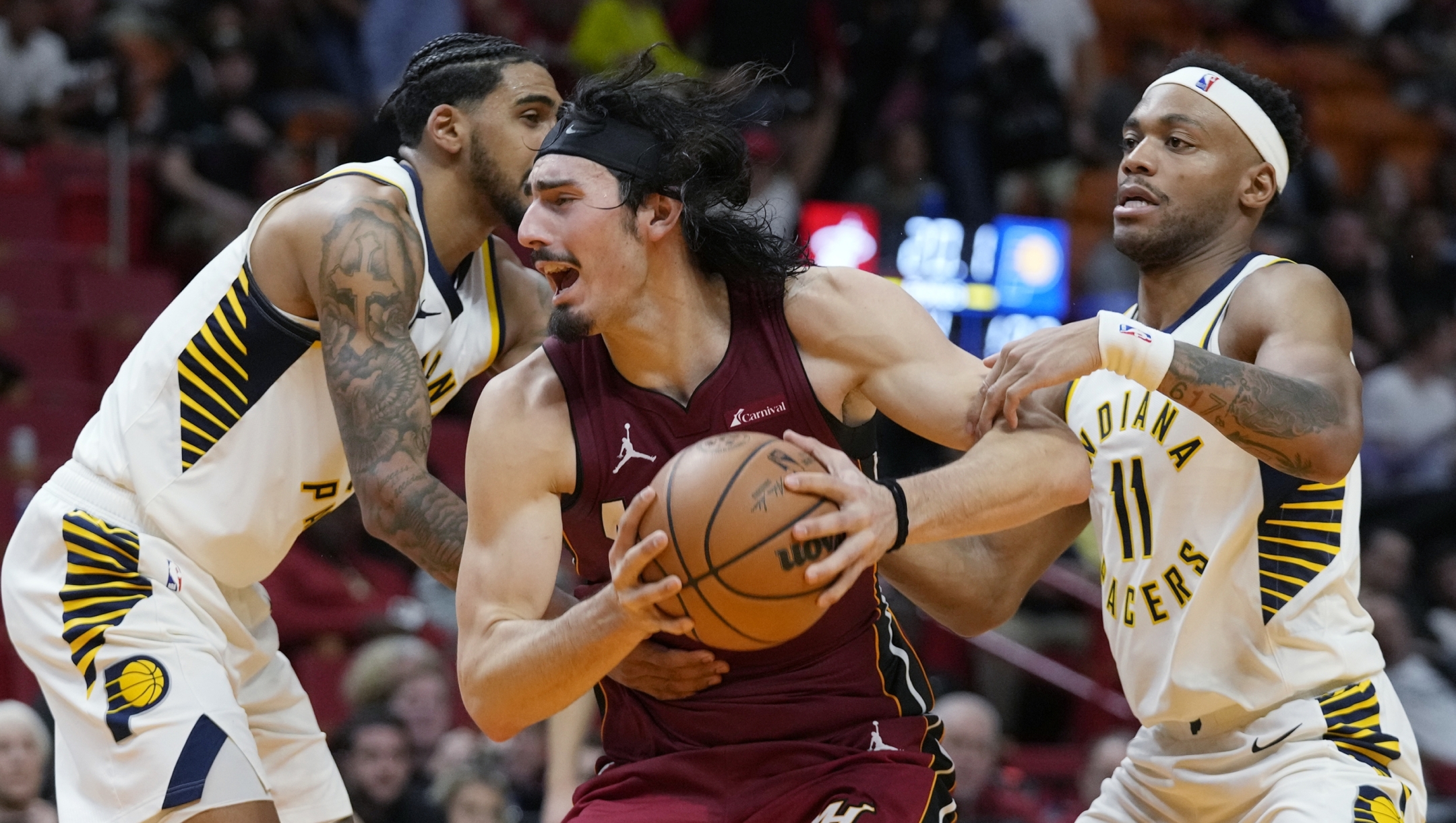 Miami Heat forward Jaime Jaquez Jr., center, grabs a rebound against Indiana Pacers guard Bruce Brown (11) and forward Obi Toppin, left, during the second half of an NBA basketball game, Thursday, Nov. 30, 2023, in Miami. (AP Photo/Wilfredo Lee)