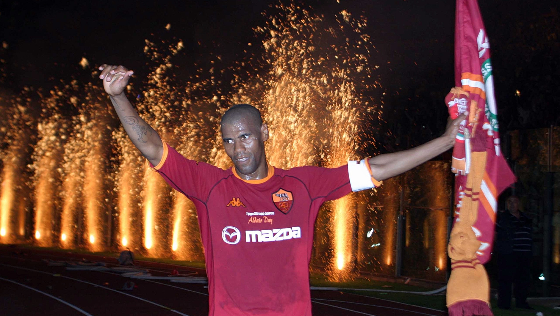 AS Roma's defender Dos Santos Aldair, of Brazil, holds a red and yellow team flag at the end of his farewell game between AS Roma and Brazil at Rome's Olympic stadium, Monday, June 2, 2003. (AP Photo/Giuseppe Calzuola)