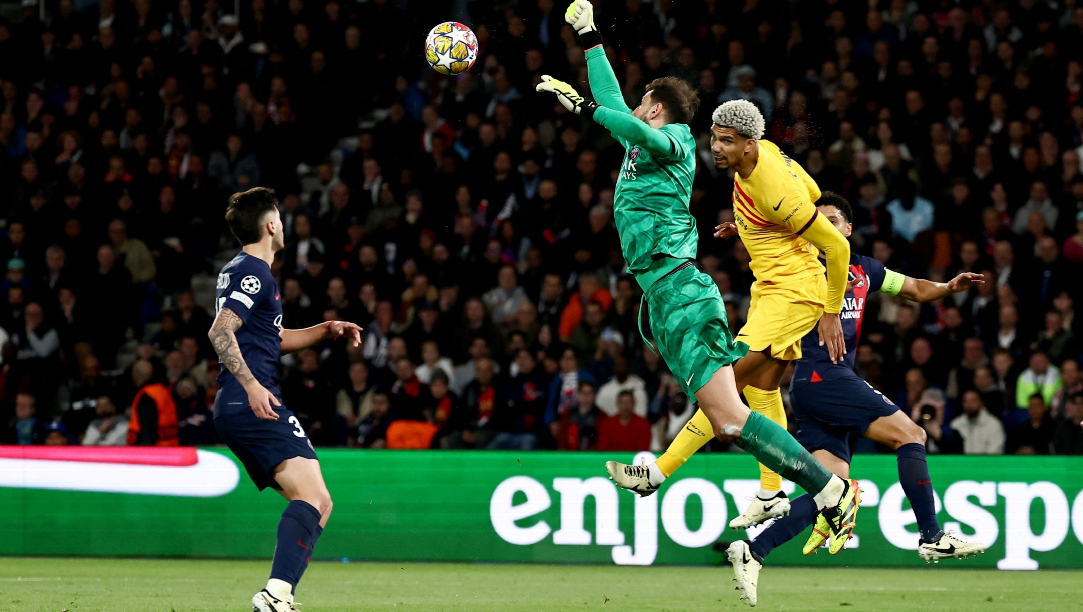 Paris Saint-Germain's Italian goalkeeper #99 Gianluigi Donnarumma (C) leaps in the air to punch the ball ahead of Barcelona's Uruguayan defender #04 Ronald Araujo (2R) during the UEFA Champions League quarter final first leg football match between Paris Saint-Germain (PSG) and FC Barcelona at the Parc des Princes stadium in Paris on April 10, 2024. (Photo by Anne-Christine POUJOULAT / AFP)