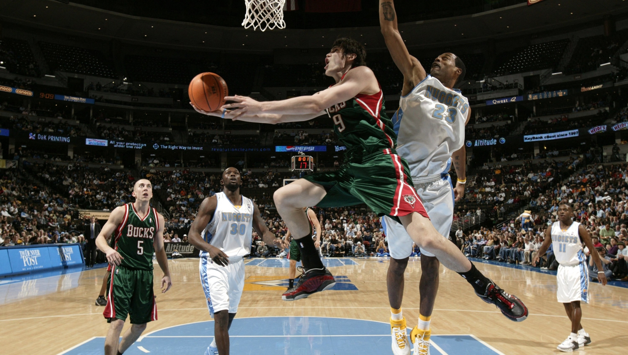 Ersan Ilyasova #19 of the Milwaukee Bucks shoots against Marcus Camby #23 of the Denver Nuggets 08 January 2006 at the Pepsi Center in Denver, Colorado.  Nathaniel S. Butler/NBAE via Getty Images/AFP  =FOR NEWSPAPERS, INTERNET, TELCOS AND TELEVISION USE ONLY= (Photo by Nathaniel S. Butler / NBAE / Getty Images via AFP)