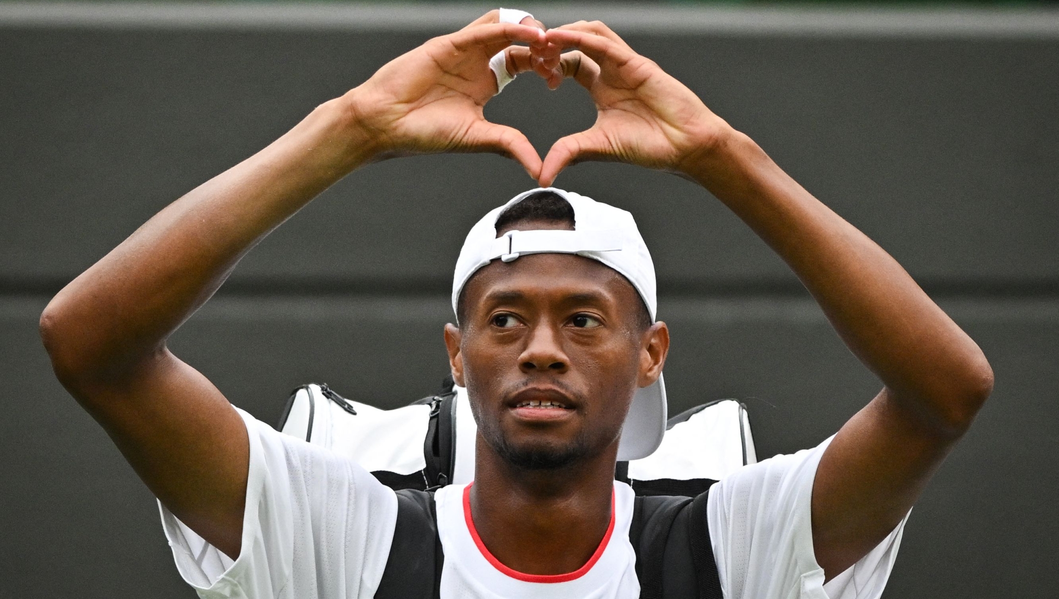 US player Christopher Eubanks does a heart with his hands as he acknowledges the audience while leaving the court following his defeat against Russia's Daniil Medvedev during their men's singles quarter-finals tennis match on the tenth day of the 2023 Wimbledon Championships at The All England Lawn Tennis Club in Wimbledon, southwest London, on July 12, 2023. (Photo by Glyn KIRK / AFP) / RESTRICTED TO EDITORIAL USE