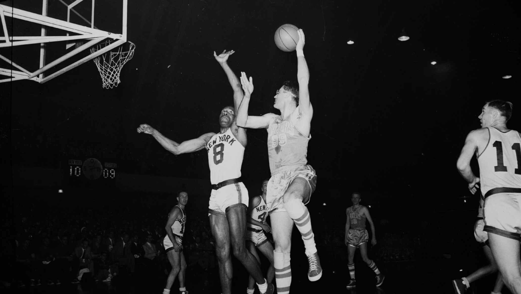 minneapolis lakers - George Mikan, right, six-foot, ten inch center for the Minneapolis lakers, goes way up to make goal as New York Knickerbockers' six-foot, seven, center Nat "Sweetwater" Clifton, 8, makes an unsuccessful attempt to thwart the score on April 8, 1953 at the 69th Regiment Armory in New York.  (AP Photo) - Fotografo: ap