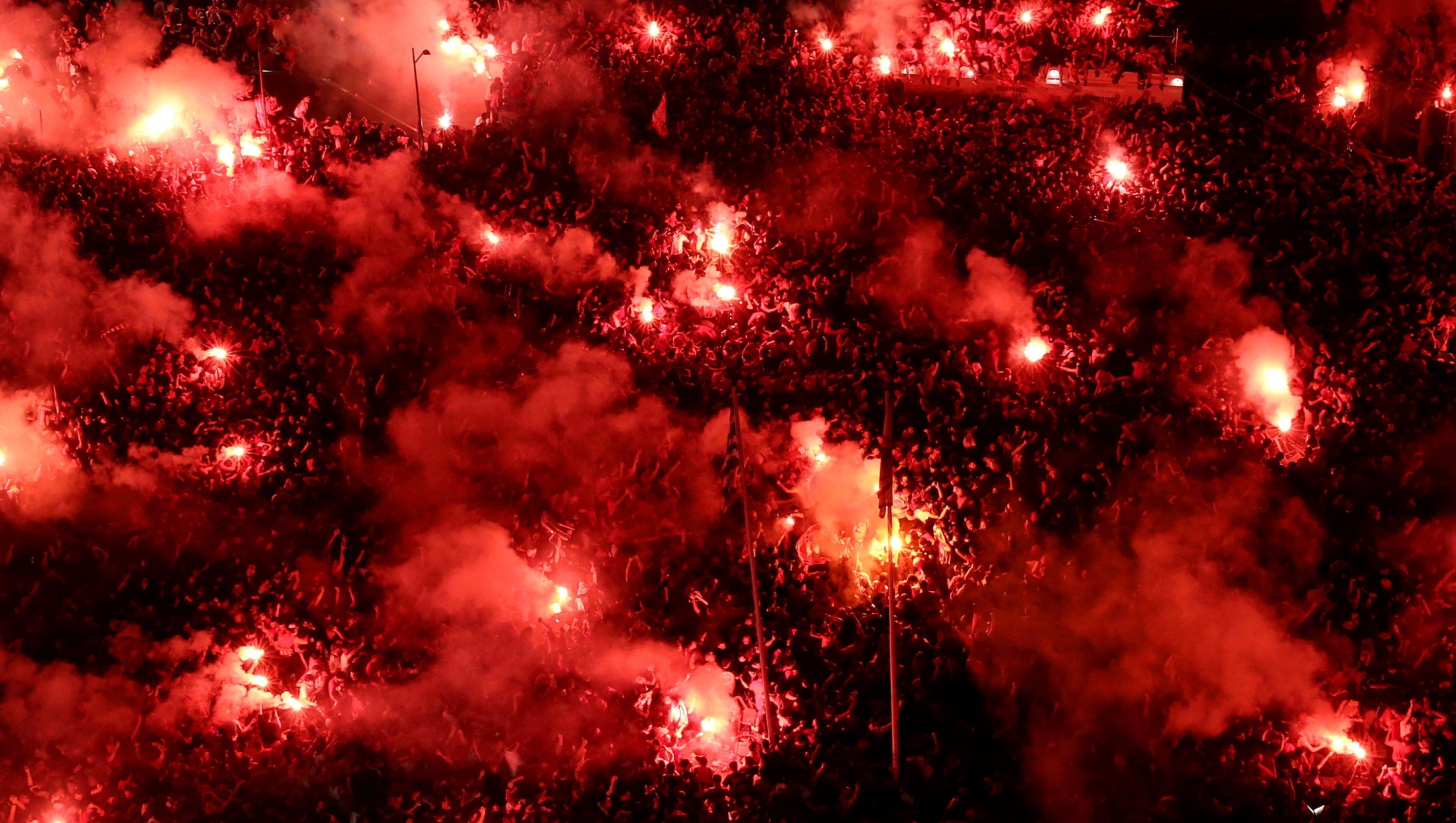 epa11378470 Olympiacos supporters light flares and fireworks as they watch a public broadcast of the UEFA Europa Conference League final soccer match of Olympiacos Piraeus against ACF Fiorentina, in Piraeus, Greece, 29 May 2024.  EPA/ORESTIS PANAGIOTOU