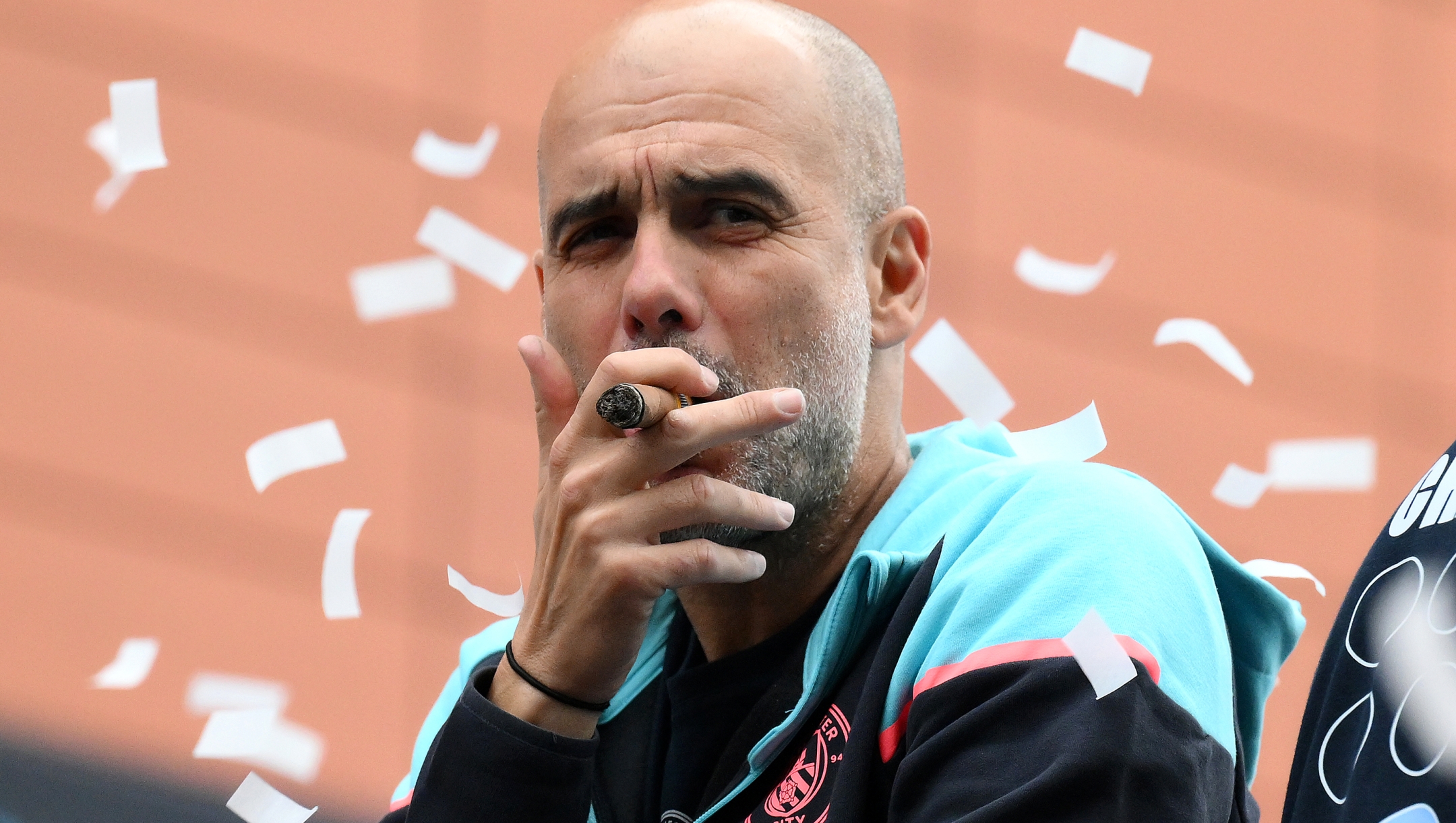 MANCHESTER, ENGLAND - MAY 26: Pep Guardiola, Manager of Manchester City, looks on as he smokes a cigar whilst on the Open Top Bus during the Manchester City trophy parade on May 26, 2024 in Manchester, England. (Photo by Ben Roberts Photo/Getty Images)