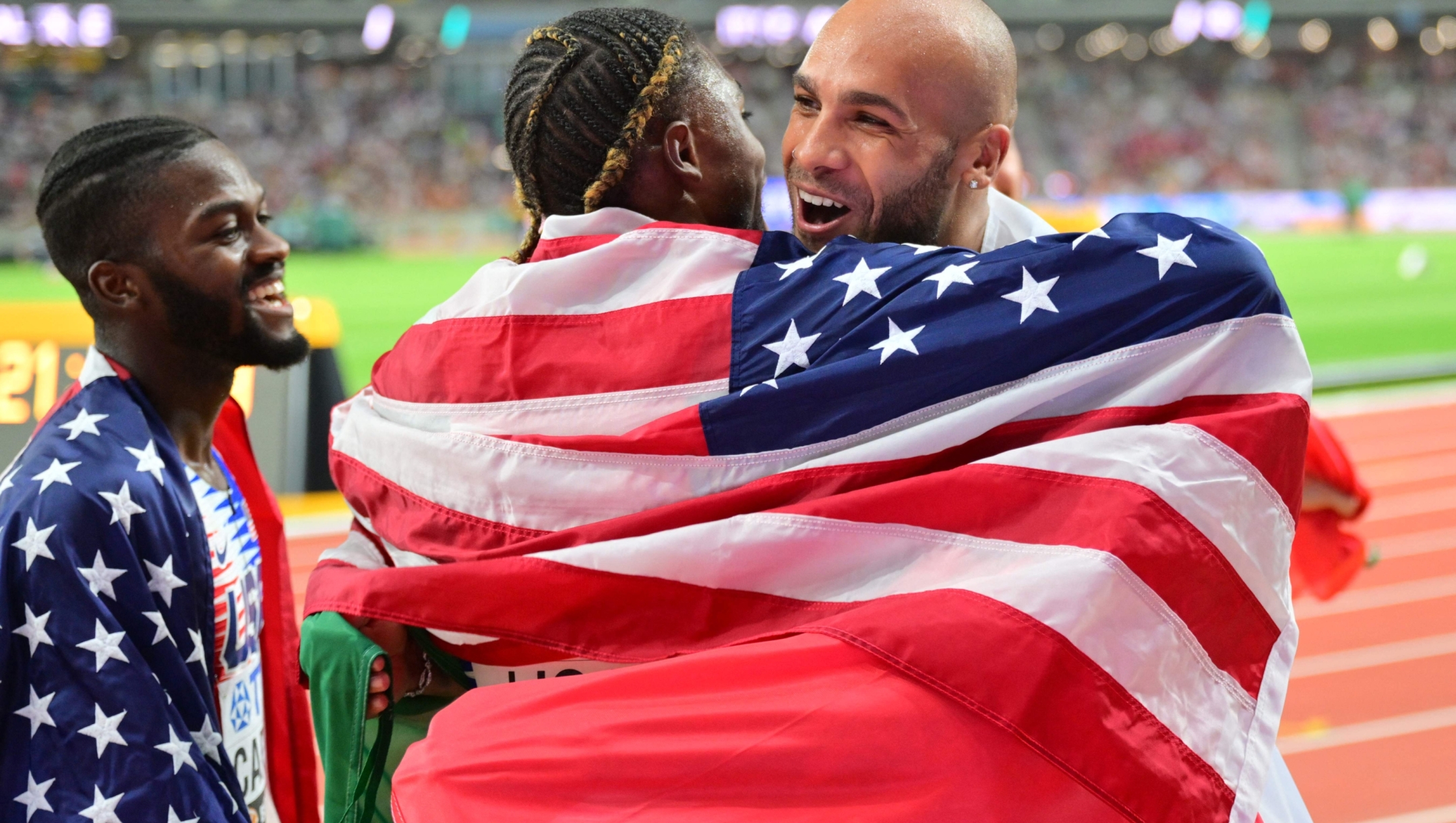 A member of Italy's silver medal team, Italy's Lamont Marcell Jacobs (R) embraces USA's Noah Lyles (C) after the USA team win the men's 4x100m relay final during the World Athletics Championships at the National Athletics Centre in Budapest on August 26, 2023. (Photo by ANDREJ ISAKOVIC / AFP)