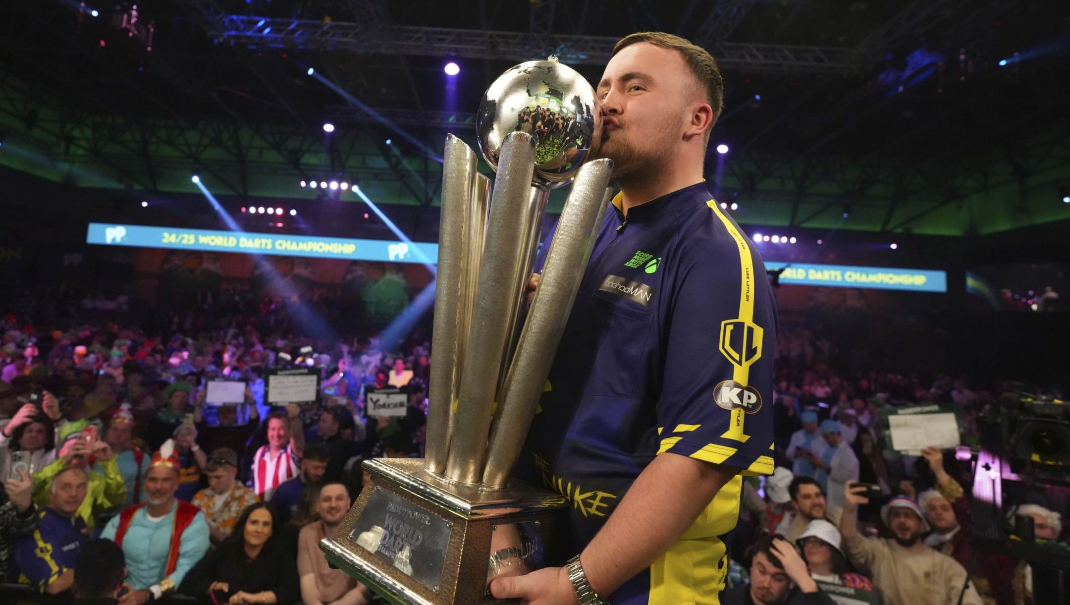 Luke Littler of England kisses the trophy after winning the final against Michael van Gerwen of the Netherlands at the World Darts Championship at Alexandra Palace in London, Friday, Jan. 3, 2025. (AP Photo/Kirsty Wigglesworth)