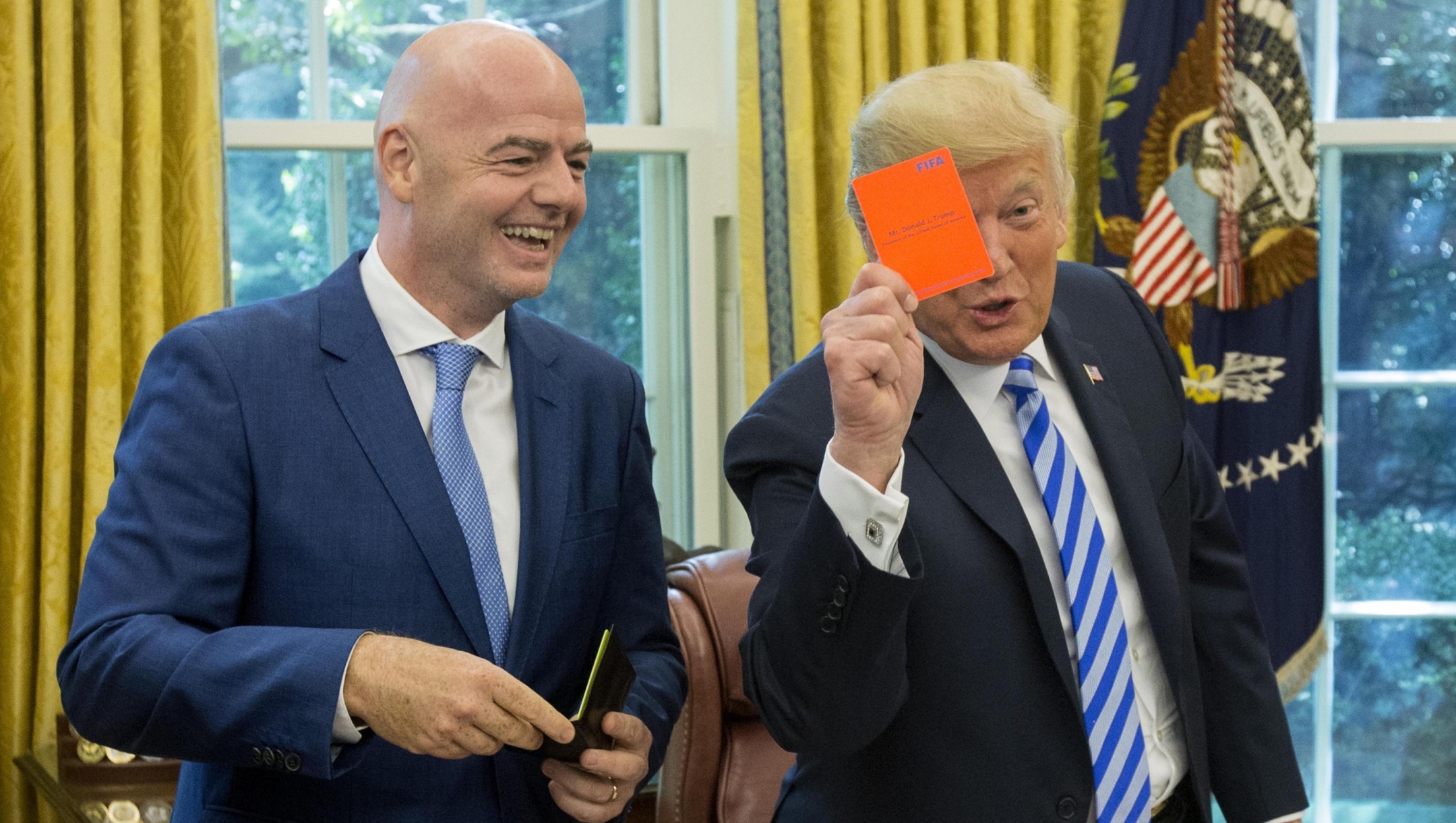 epa06979412 US President Donald J. Trump (R) holds up a FIFA red card that has his name on it, toward members of the news media, given to him by President of FIFA Gianni Infantino (L) during their meeting in the Oval Office of the White House in Washington, DC, USA, 28 August 2018. Along with the Canada and Mexico, the US will host the 2026 FIFA World Cup.  EPA/MICHAEL REYNOLDS