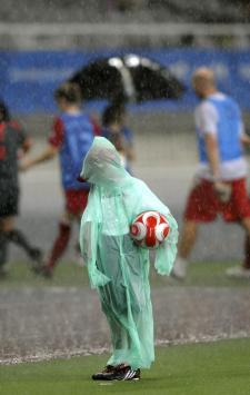 A ball boy stands on the pitch as the players of both teams and referees leave the field due to the thundershowers during the 2008 Beijing Olympic Games women's quarter-final football match between Canada and the US at the Shanghai Stadium on August 15, 2008.  AFP PHOTO/LIU Jin (Photo by LIU JIN / AFP)