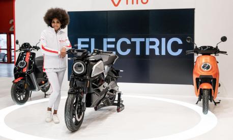 A model poses by motorcycles and motorbikes on display on the NIU stand at EICMA, the 78th edition of the International Bicycle and Motorcycle exhibition during its opening on November 23, 2021 in Milan. (Photo by Piero CRUCIATTI / AFP)