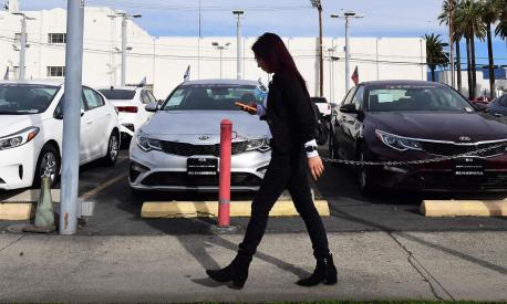 A pedestrian walks past a certified pre-owned car sales lot in Alhambra, California on January 12, 2022. - The seven percent increase in the Labor Department's consumer price index (CPI) over the 12 months to December was the highest since June 1982, as prices rose for an array of goods especially housing, cars and food. (Photo by Frederic J. BROWN / AFP)