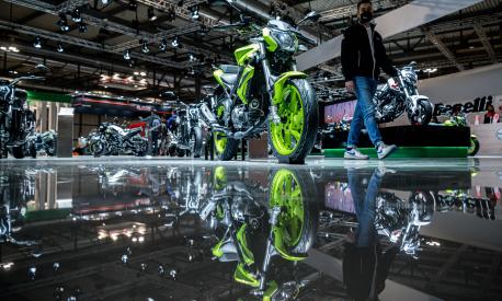 A man walks past a Benelli BN125 motorbike on display on the Benelli stand at EICMA, the 78th edition of the International Bicycle and Motorcycle exhibition during its opening on November 23, 2021 in Milan. (Photo by Piero CRUCIATTI / AFP)