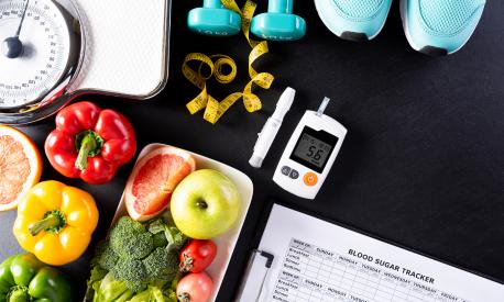 World diabetes day, Healthcare and medical concept. Healthy food including fresh fruits, vegetables, weight scale, sports shoes, dumbells, measure tape and diabetic measurement set on black background.