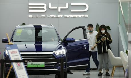People visit a Chinese automaker BYD store on Wednesday, March 16, 2022, in Beijing. China's government tried Wednesday to reassure jittery investors by promising support for its struggling real estate industry, internet companies and entrepreneurs after regulatory crackdowns caused stock prices to plunge. (AP Photo/Ng Han Guan)