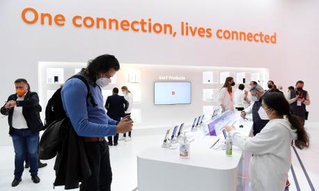 Visitors look at phones on Xiaomi's stand on the opening day of the MWC (Mobile World Congress) in Barcelona on February 28, 2022. - The world's biggest mobile fair is held from February 28 to March 3, 2022. (Photo by Josep LAGO / AFP)