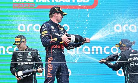 Second placed Mercedes' British driver Lewis Hamilton (R), winner Red Bull Racing's Dutch driver Max Verstappen (C) and third placed Mercedes' British driver George Russell spray with champagne as they celebrate on the podium after the Formula One Hungarian Grand Prix at the Hungaroring in Mogyorod near Budapest, Hungary, on July 31, 2022. (Photo by Attila KISBENEDEK / AFP)